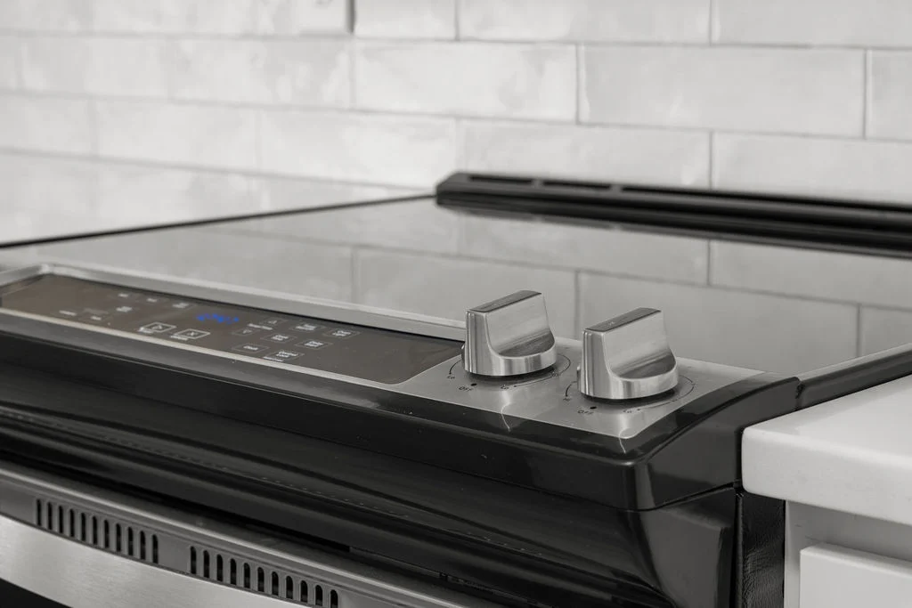 Sleek modern stove with digital controls and knobs against white tile, featured in Pratt Home Builders in Chattanooga TN kitchen.