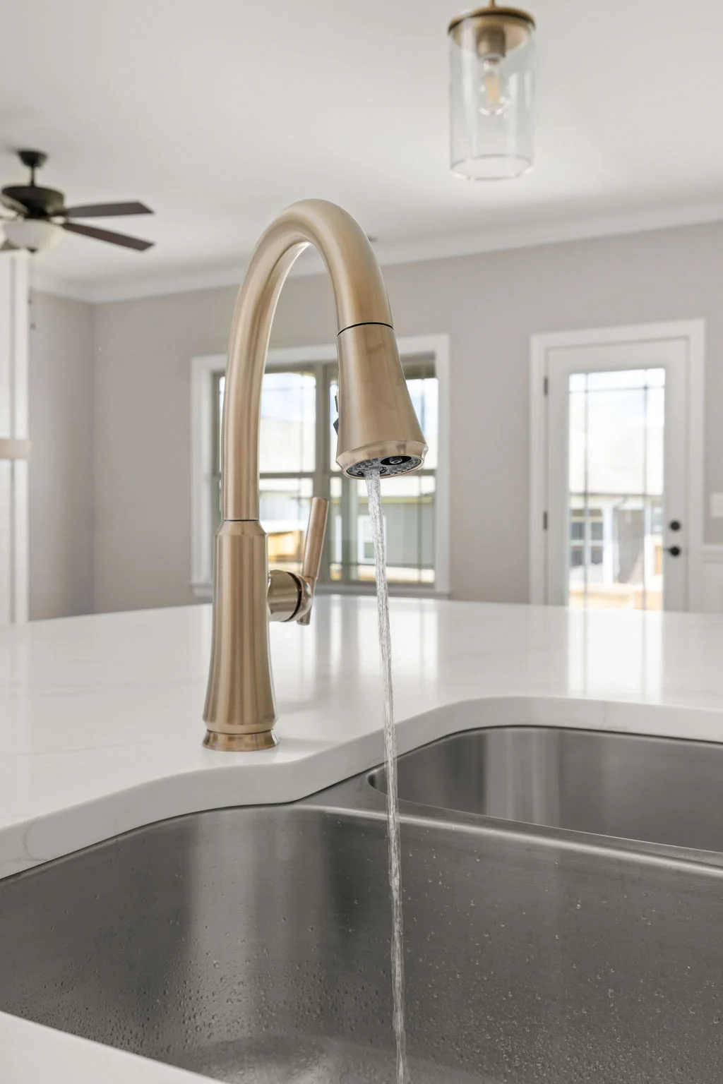 Modern kitchen faucet with running water, stainless steel sink, and elegant fixtures by Pratt Home Builders in Chattanooga TN.