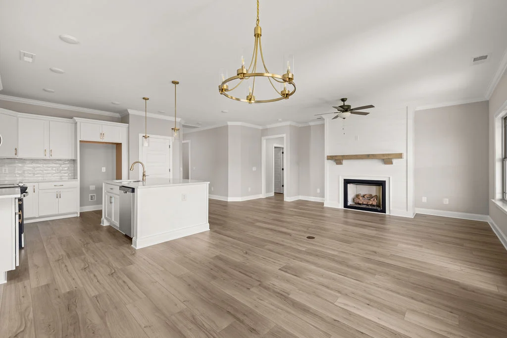 Open floor plan featuring a modern kitchen, elegant chandelier, and cozy fireplace, crafted by Pratt Home Builders in Chattanooga TN.