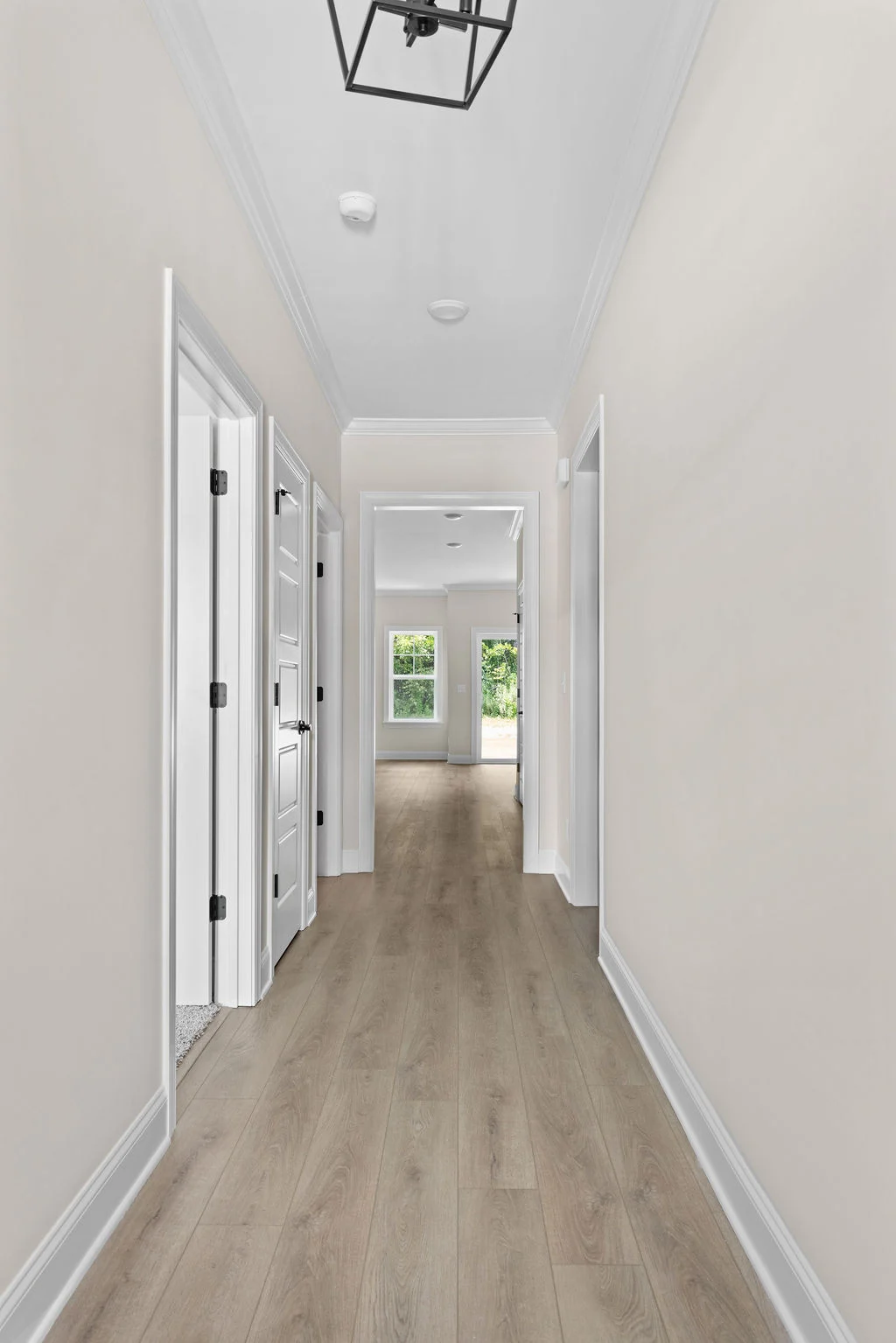 New Home in Chattanooga TN. Bright hallway with light wood flooring, beige walls, and modern light fixture by Pratt Home Builders.
