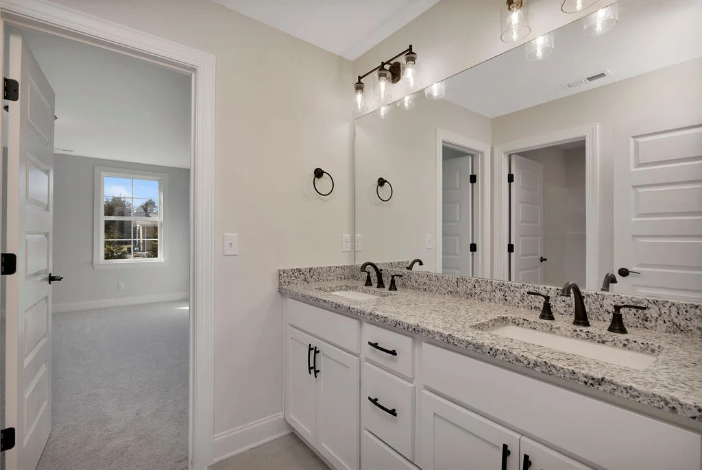 Modern bathroom with granite double sink, elegant lighting, and white cabinetry, crafted by Pratt Home Builders in Chattanooga, TN.