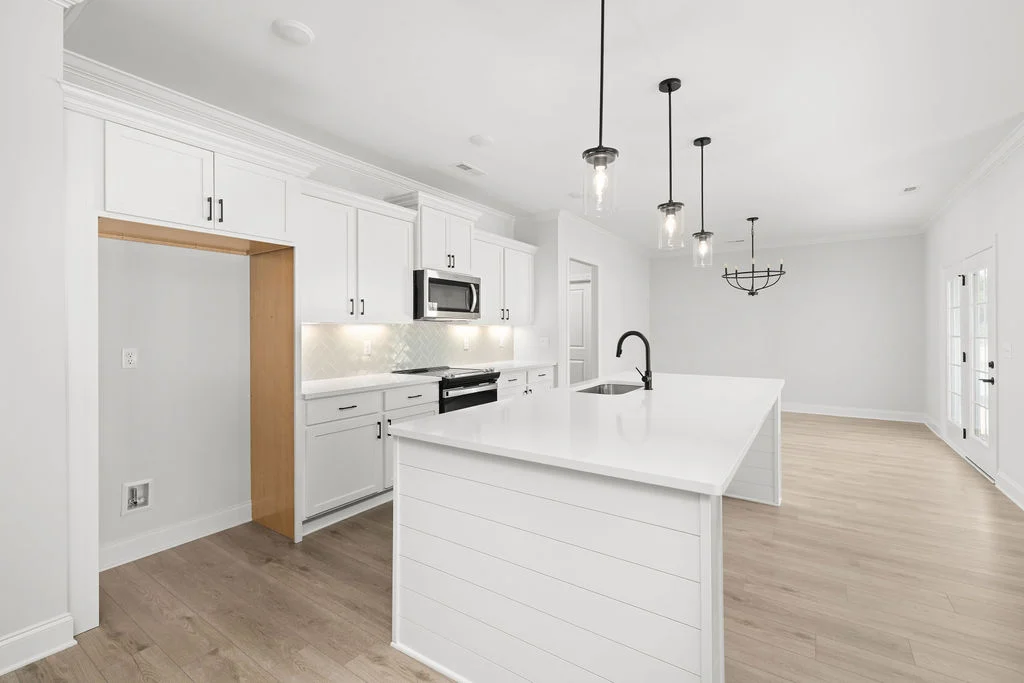 Modern kitchen with white cabinets, quartz island, and black accents by Pratt Home Builders in Chattanooga TN. Open concept with wooden floors.
