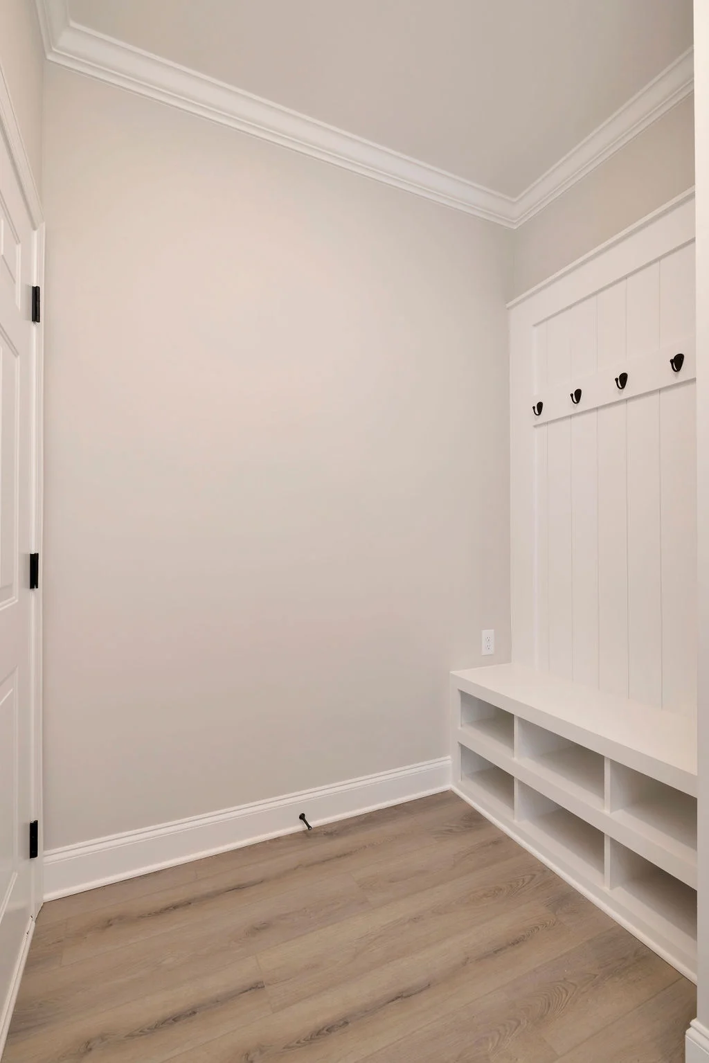 Mudroom by Pratt Home Builders in Chattanooga TN. Features beige walls, wood floor, bench, cubbies, and hooks for storage.