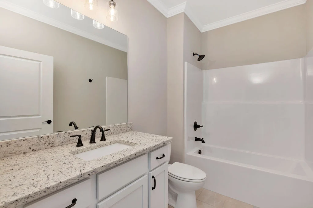 Modern bathroom with granite countertop, dual sinks, bathtub, and beige walls by Pratt Home Builders in Chattanooga TN.