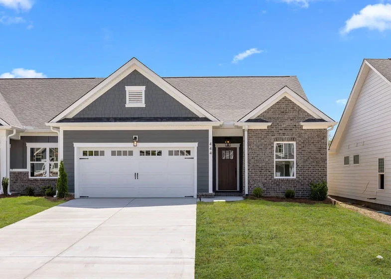 Modern single-story home with brick facade, white garage, and manicured lawn, built by Pratt Home Builders in Chattanooga TN.
