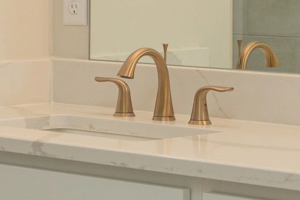 Brushed bronze bathroom faucet with dual handles on a marble countertop by Pratt Home Builders in Chattanooga TN.
