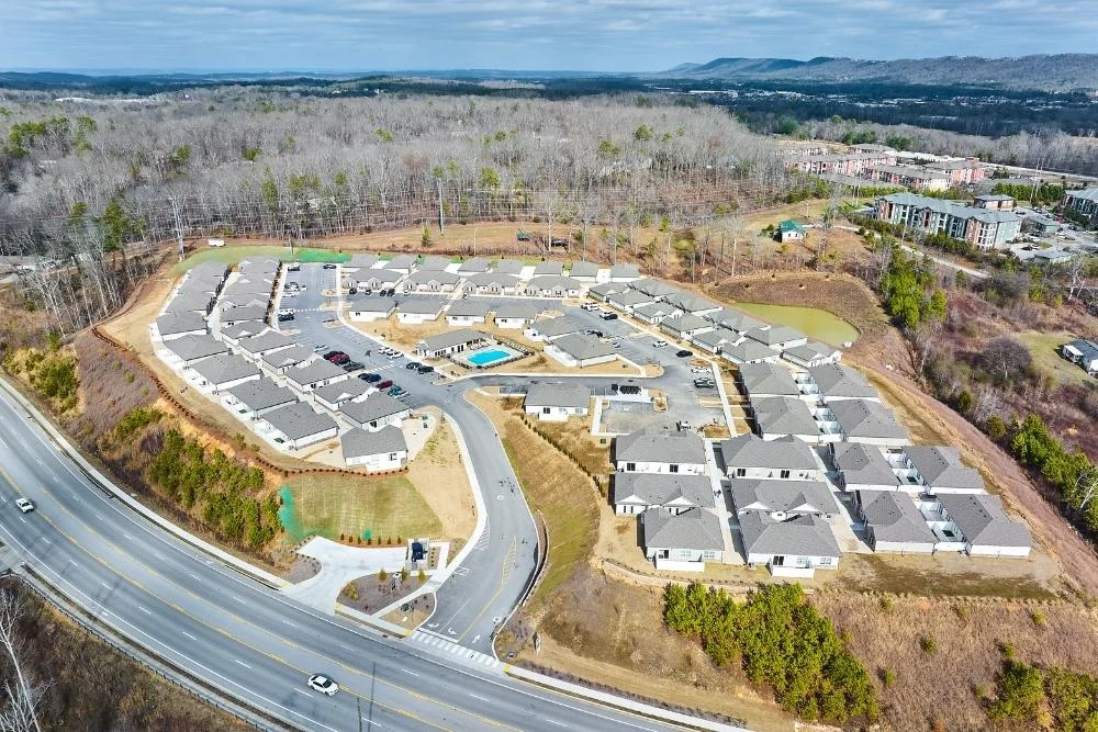 Build Now, Move In 2026 Why It Makes Smart Financial Sense Aerial view of residential development by Pratt Home Builders in Chattanooga TN, with houses and a central pool, surrounded by wooded areas.