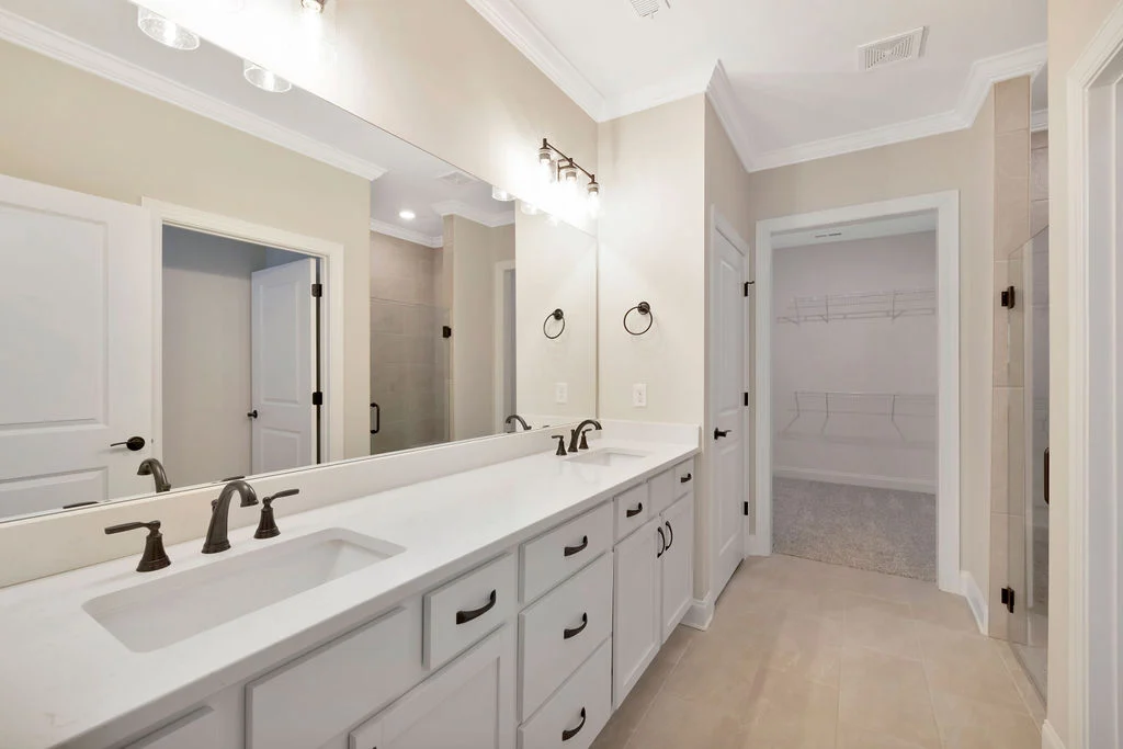 Modern bathroom with double vanity, sleek fixtures, and adjacent walk-in closet by Pratt Home Builders in Chattanooga TN.
