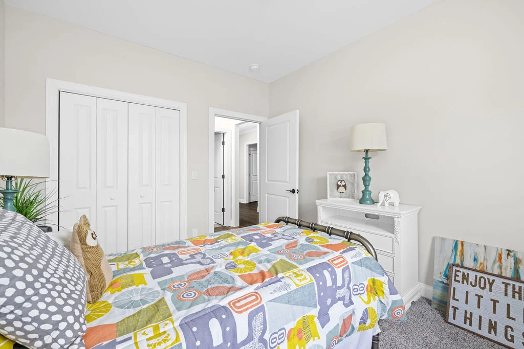 Bright bedroom or office space with colorful bedding, white furniture, and wall art. Designed by Pratt Home Builders in Chattanooga TN.