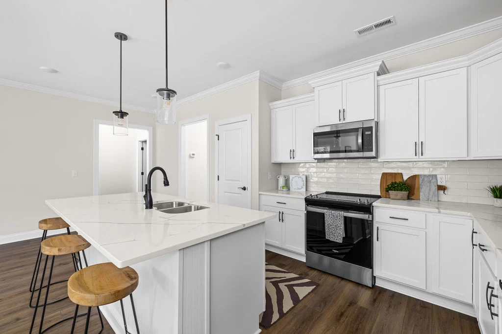 Modern kitchen by Pratt Home Builders in Chattanooga TN with white cabinets, stainless steel appliances, and a marble island with wooden stools.