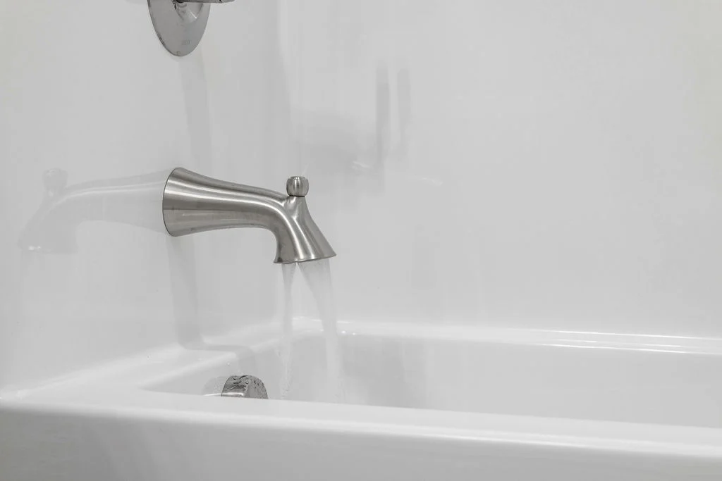 Modern bathtub with sleek silver faucet releasing water, featured by Pratt Home Builders in Chattanooga TN.