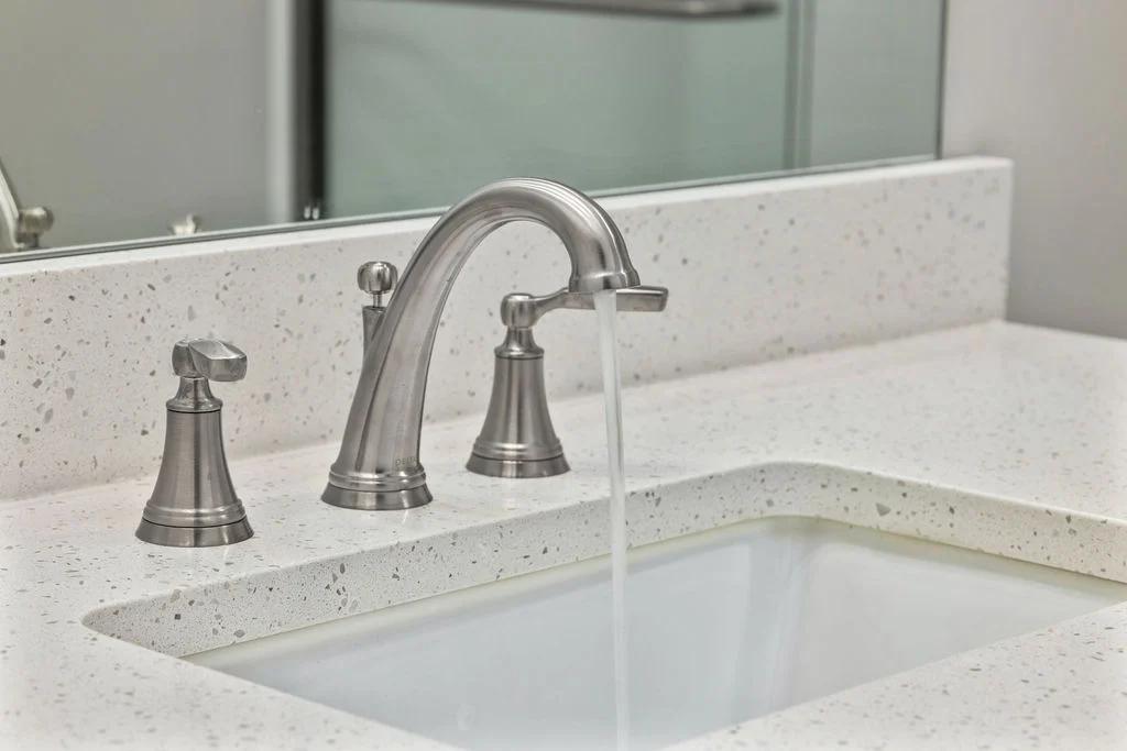Modern faucet with running water on a speckled countertop, showcasing Pratt Home Builders in Chattanooga TN design.