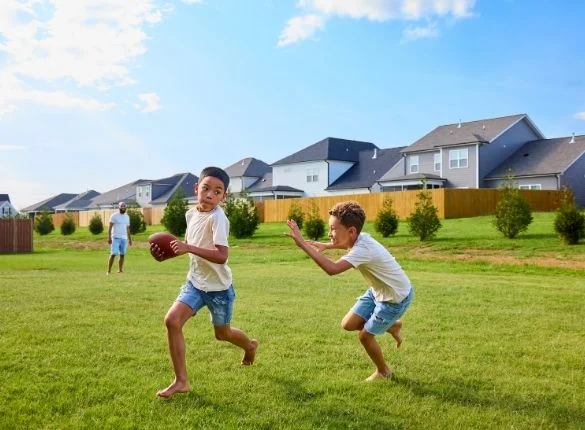 Kids playing football in Pratt Home Builders Community Kids playing football in Pratt Home Builders Community