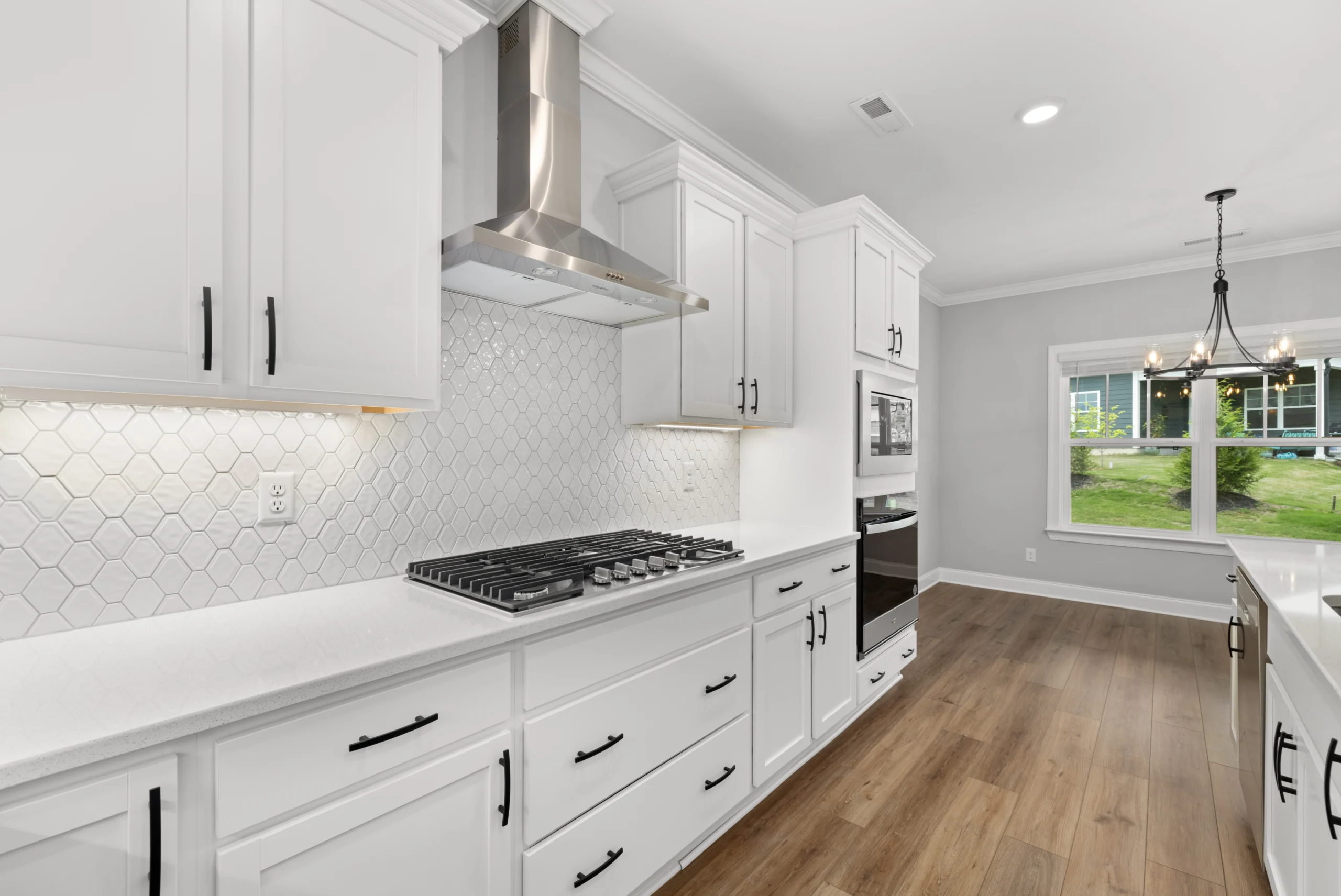 New Home Chattanooga TN. Modern kitchen with white cabinets, hexagonal tile backsplash, and stainless steel appliances by Pratt Home Builders.
