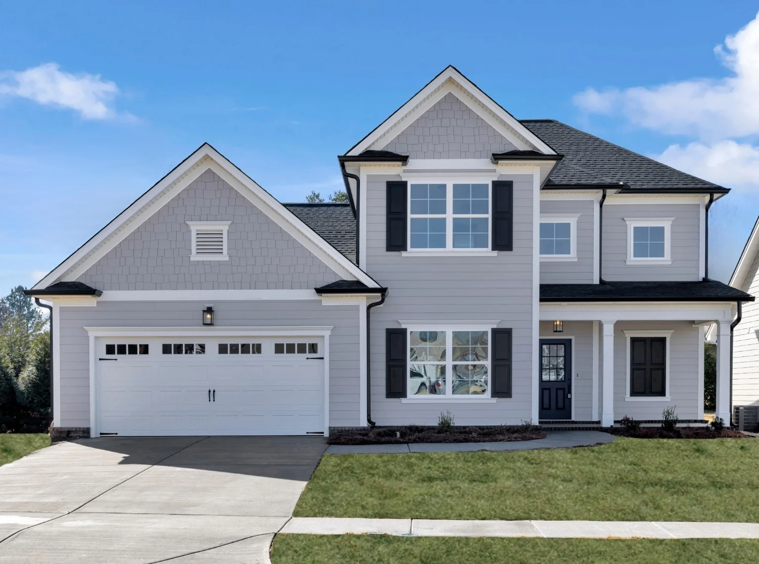 New home Chattanooga TN. Two-story gray house with garage, black shutters, and white trim. Built by Pratt Home Builders, under a clear blue sky.