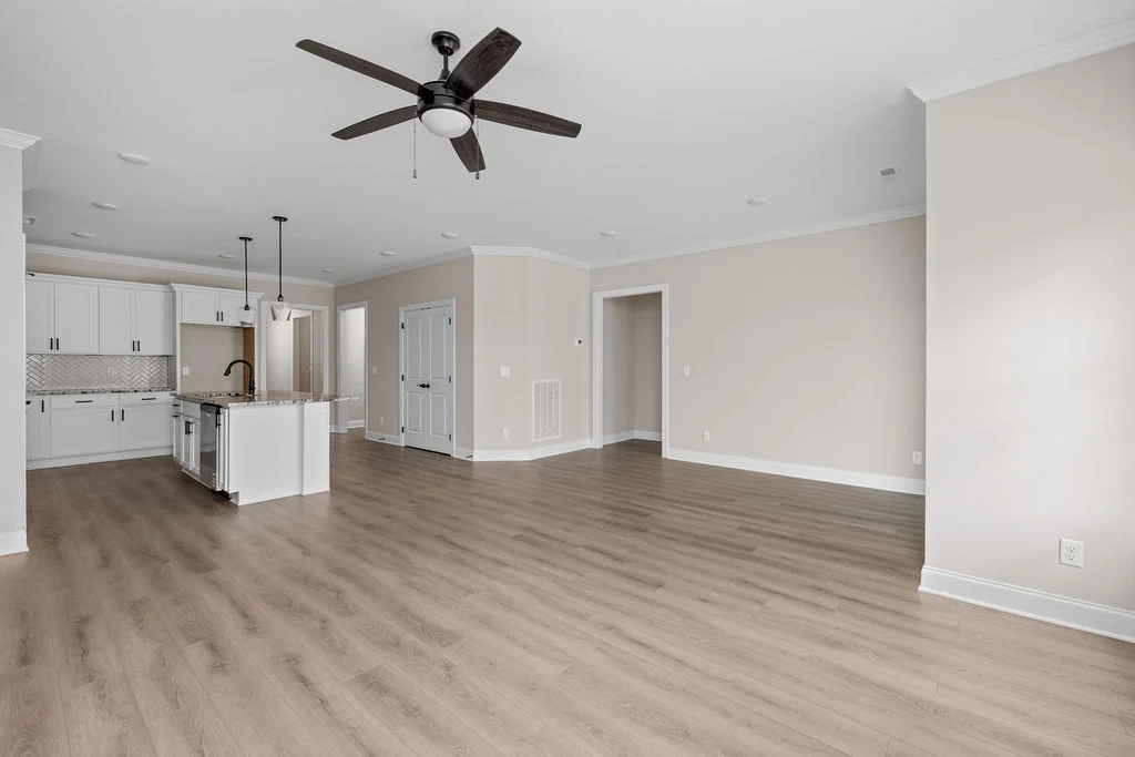 Spacious modern living area with ceiling fan, open kitchen featuring an island and pendant lights by Pratt Home Builders in Chattanooga, TN.