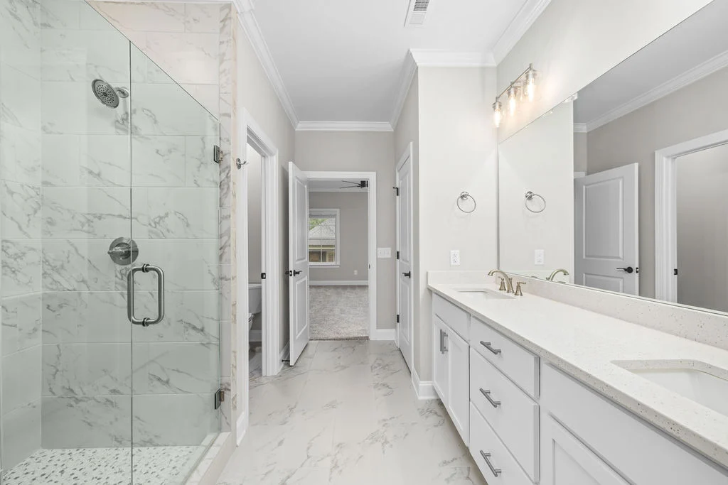 New Home Chattanooga TN. Elegant bathroom designed by Pratt Home Builders, featuring a marble-tiled shower and dual-sink vanity with sleek fixtures.