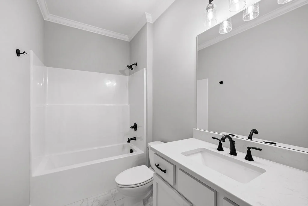 New Home Chattanooga TN. Modern bathroom with white fixtures, black hardware, a bathtub, and a double vanity by Pratt Home Builders.