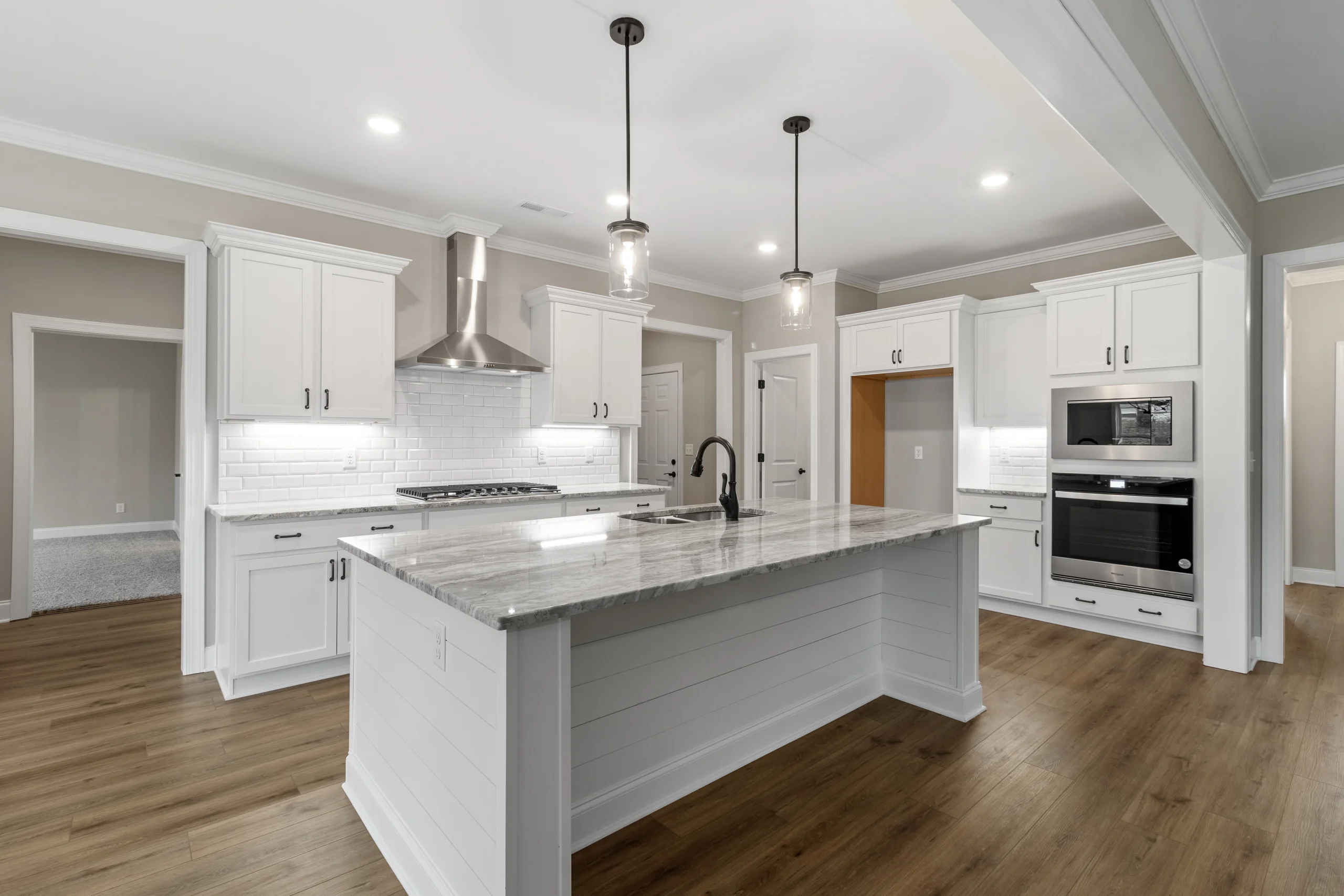 New Home Chattanooga TN. Spacious kitchen with white cabinets, marble island, pendant lights, and stainless appliances. Built by Pratt Home Builders.