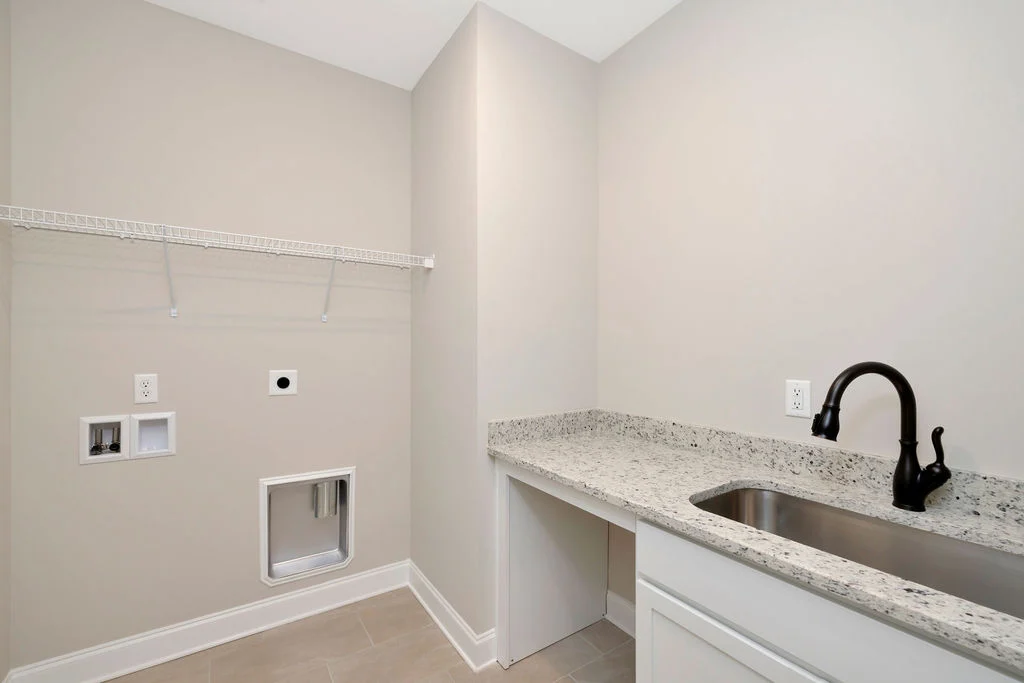 New Home Chattanooga TN. Modern laundry room by Pratt Home Builders with granite countertop, under-mount sink, and wall-mounted wire shelf.