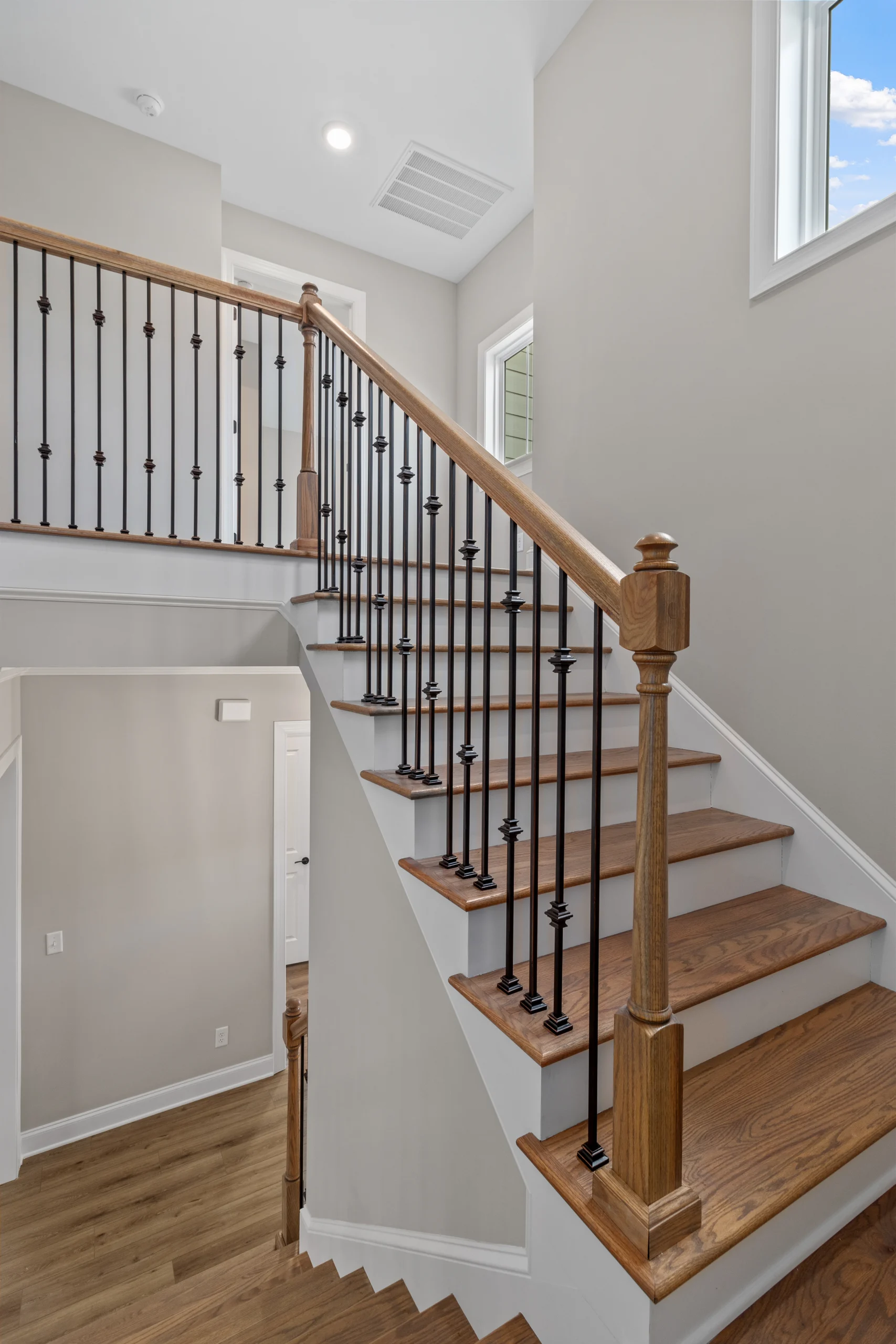 New Home Chattanooga TN. Elegant wooden staircase with black iron balusters and light gray walls, designed by Pratt Home Builders.