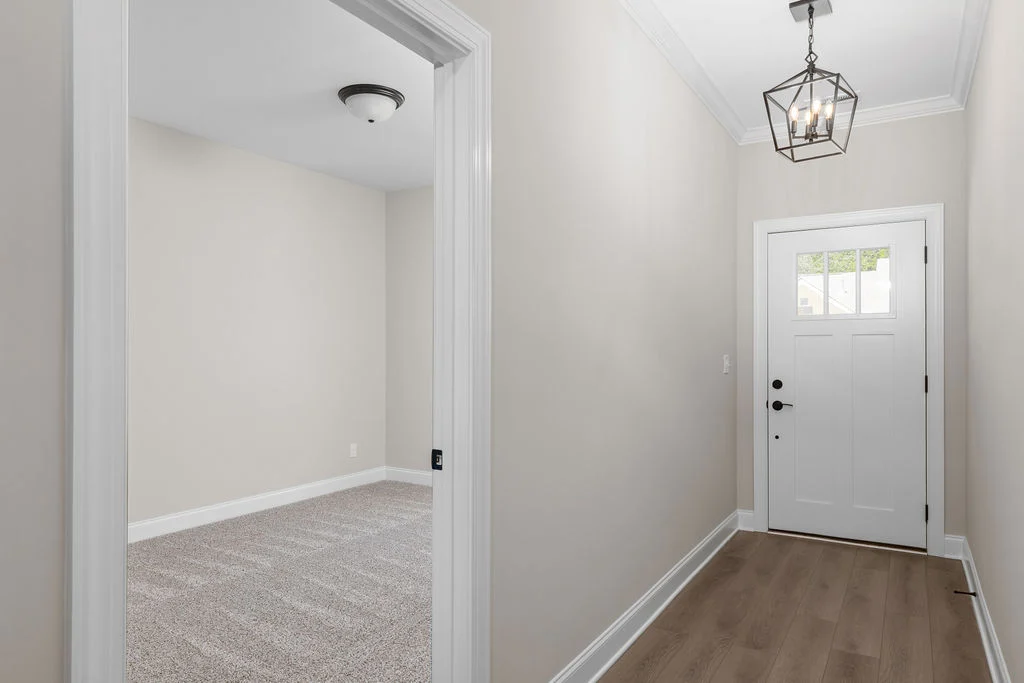 Bright hallway with wood flooring, white walls, and modern lantern light fixture; designed by Pratt Home Builders in Chattanooga TN.