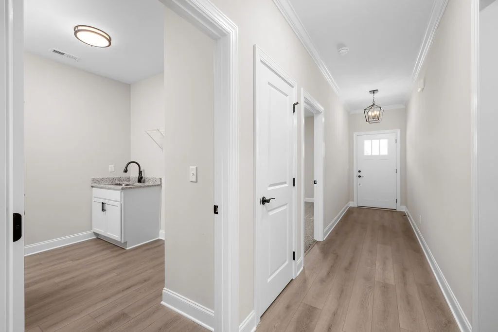 New Home Chattanooga TN. Bright hallway with hardwood floors, a utility sink, and a white door, design by Pratt Home Builders.
