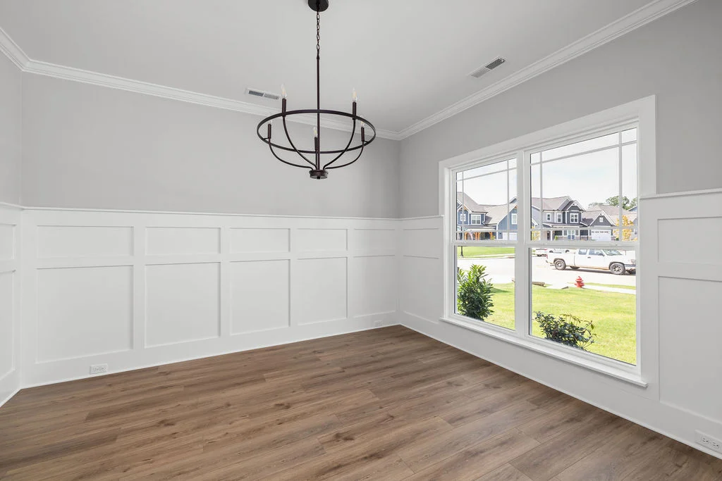 New Home Chattanooga TN. Bright room with large windows, wooden floor, and modern chandelier, showcasing Pratt Home Builders craftsmanship.