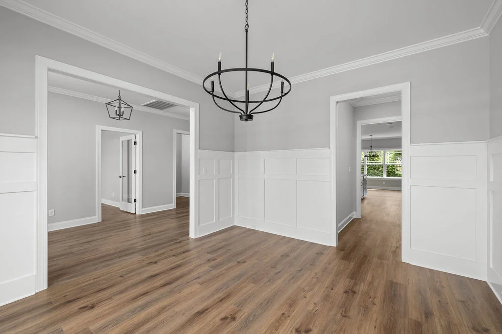 New Home Chattanooga TN. Spacious, modern interior with wood flooring, white wainscoting, and black chandeliers by Pratt Home Builders.