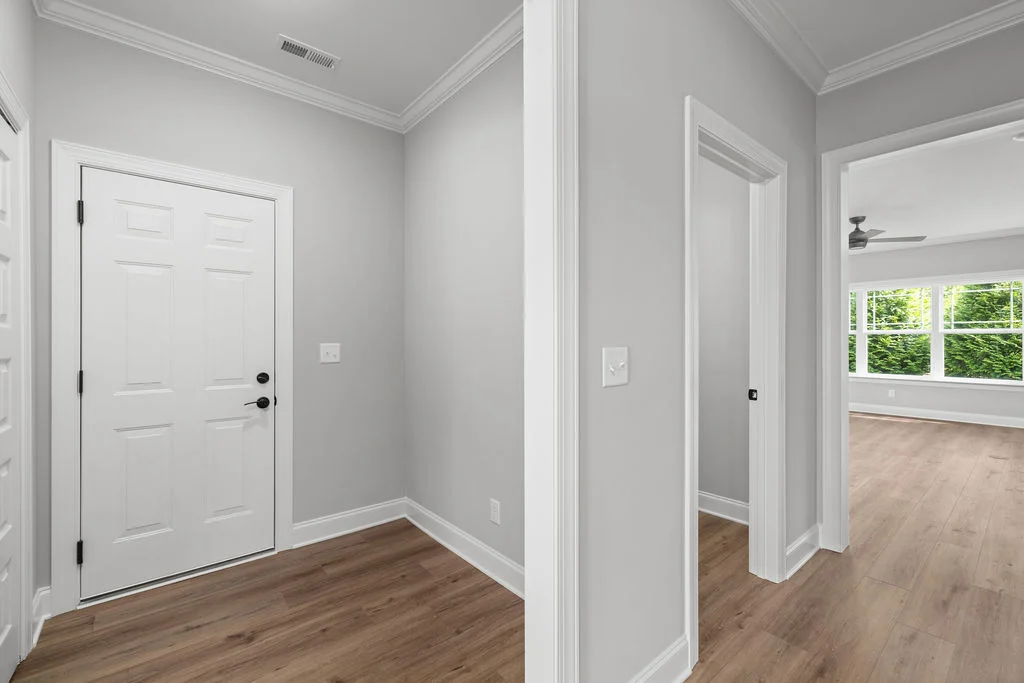 New Home Chattanooga TN. Modern entryway with hardwood floors, white doors, and a glimpse of a bright room by Pratt Home Builders.
