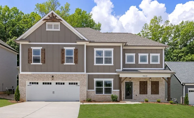 Two-story modern house by Pratt Home Builders in Chattanooga TN, featuring a large driveway, beige siding, and decorative window shutters.