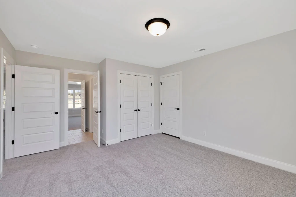 New Home Chattanooga TN. Empty, carpeted room with three white doors and a ceiling light fixture. Built by Pratt Home Builders.