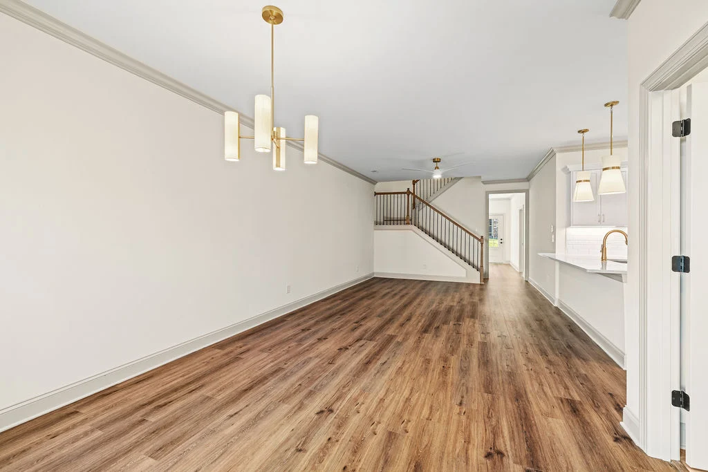Spacious dining and kitchen area with wooden floors, modern lighting, and staircase by Pratt Home Builders in Chattanooga TN.