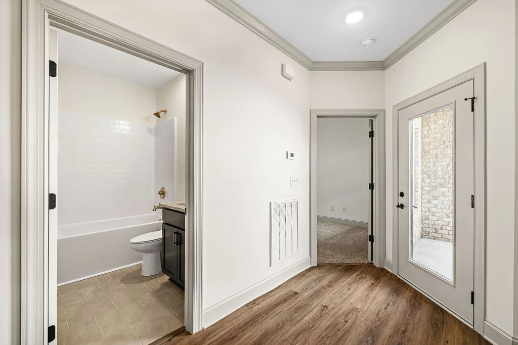 Bright hallway with wood flooring, open bathroom, and patio door designed by Pratt Home Builders in Chattanooga TN.