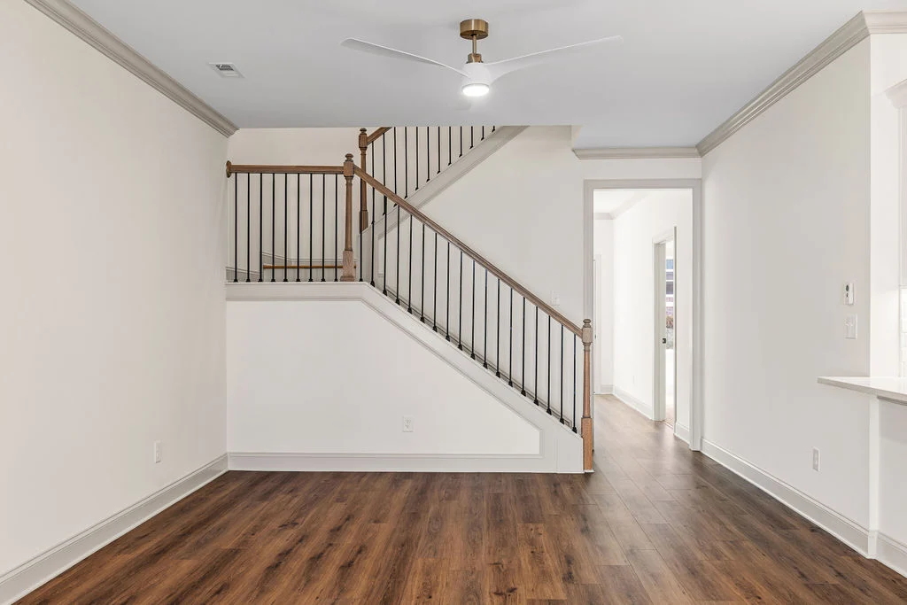 Bright interior with wooden floors, a modern ceiling fan, and stairs featuring a wooden railing. Pratt Home Builders, Chattanooga TN.