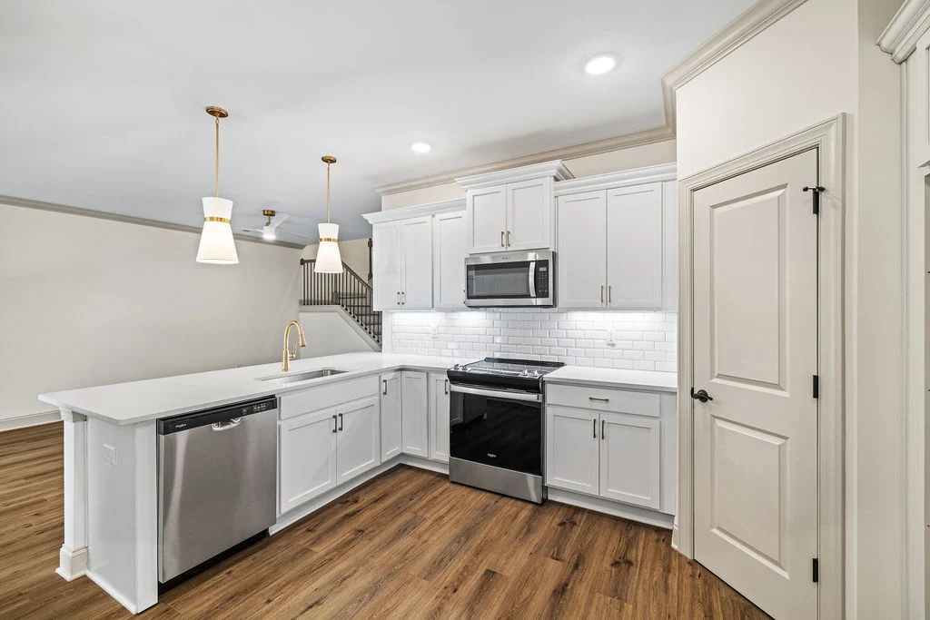 New Home Chattanooga TN. Modern kitchen with white cabinets, stainless steel appliances, and wood flooring by Pratt Home Builders.