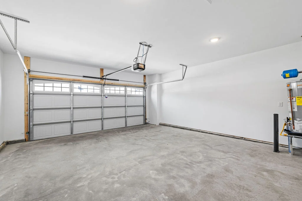 Spacious two-car garage with gray floor, white walls, and a garage door opener system by Pratt Home Builders in Chattanooga, TN.