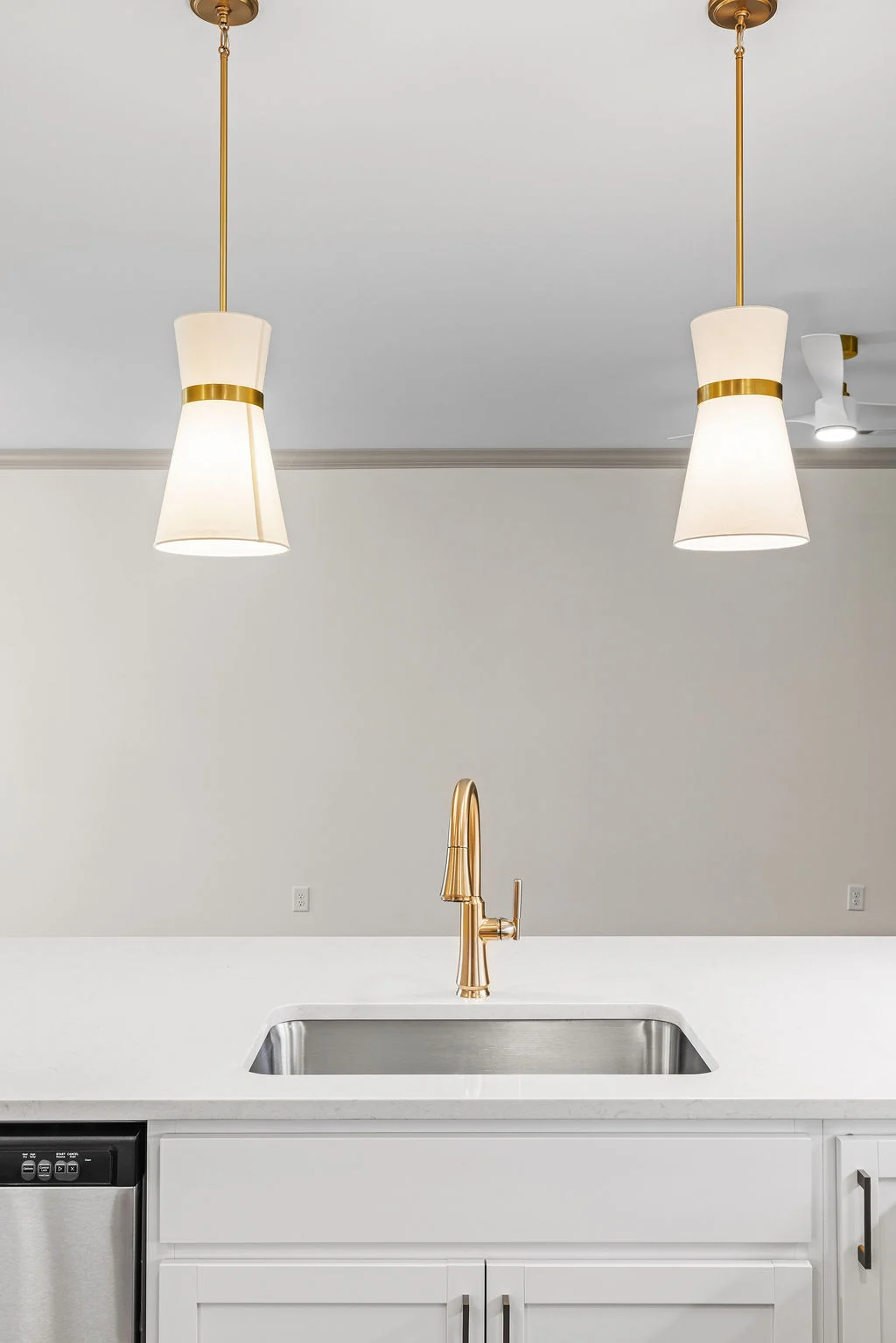 Modern kitchen with gold faucet, white counter, pendant lights by Pratt Home Builders in Chattanooga TN.