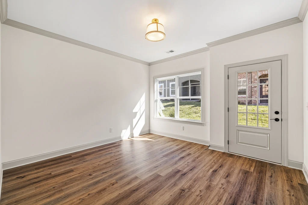 Bright room with wood flooring, large window, and glass door by Pratt Home Builders in Chattanooga TN. White walls and ceiling light fixture.