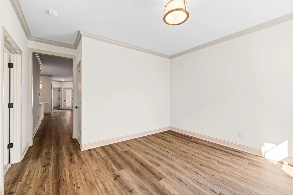 Empty room with wood flooring and light walls, featuring an open doorway leading to a hallway. Built by Pratt Home Builders in Chattanooga TN.