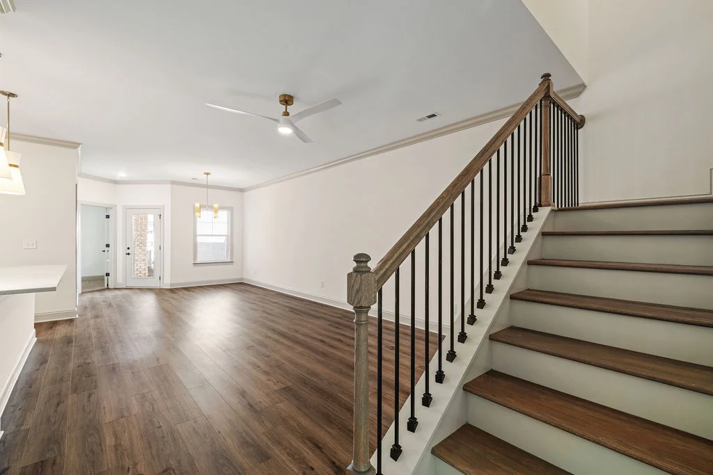Spacious living area with wooden floors, open stairs, modern ceiling fan, by Pratt Home Builders in Chattanooga TN.