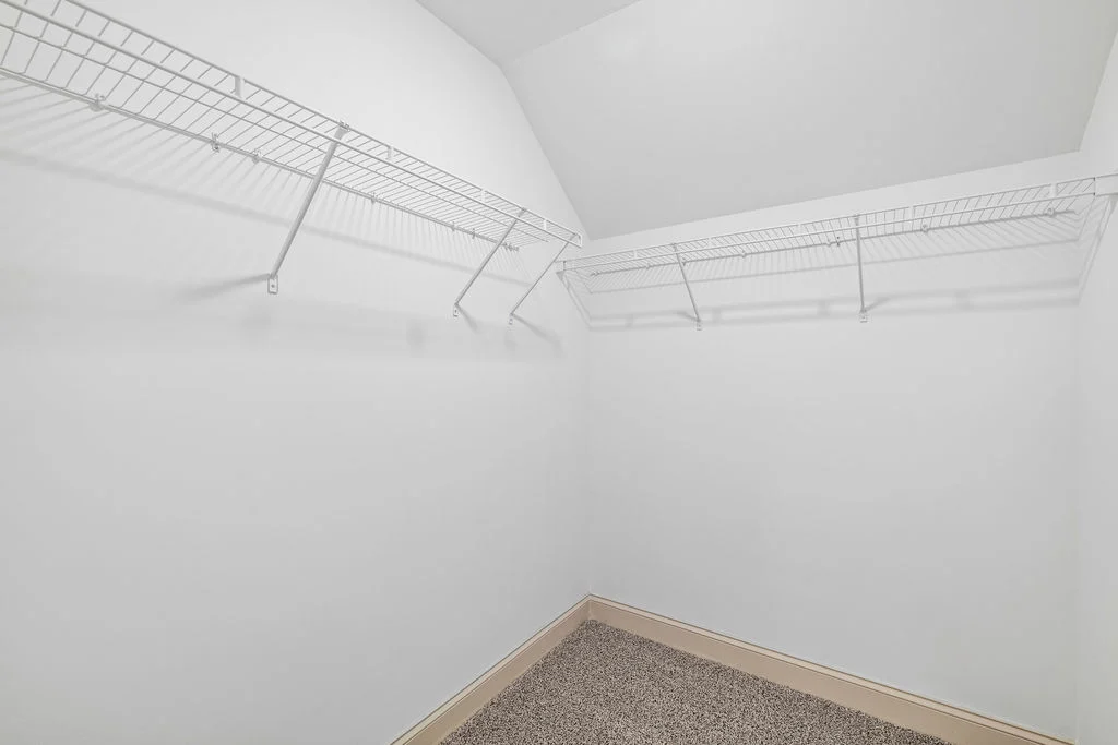 Spacious white closet with wire shelving by Pratt Home Builders in Chattanooga TN. Carpeted floor, ample storage space.