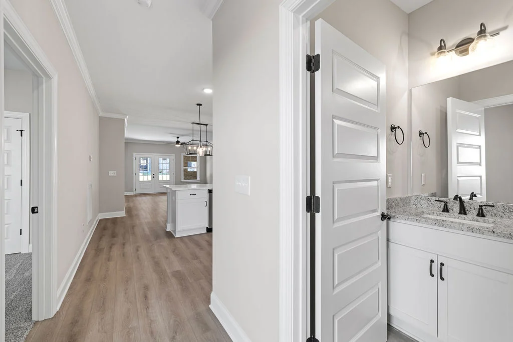 Modern interior with light wood floors, open kitchen, and dual-sink bathroom. Designed by Pratt Home Builders in Chattanooga TN.
