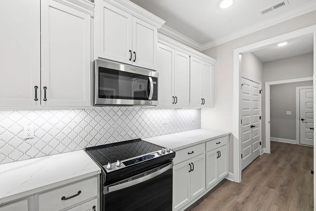 New Home Chattanooga TN. Sleek kitchen with white cabinets, tile backsplash, and modern appliances. Designed by Pratt Home Builders.