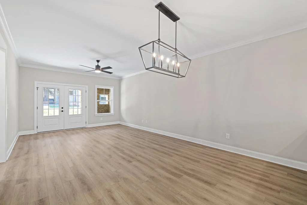 New Home Chattanooga TN. Spacious, empty living room with modern chandelier, ceiling fan, light wood flooring by Pratt Home Builders.