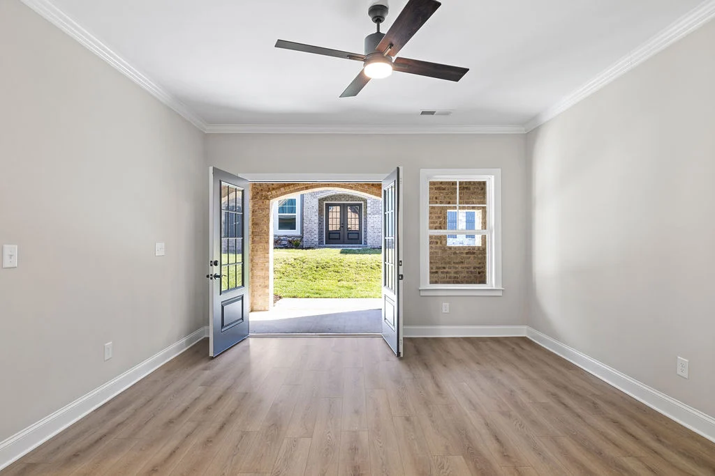Bright room with wood flooring, open double doors leading outside, and a ceiling fan. Built by Pratt Home Builders in Chattanooga TN.