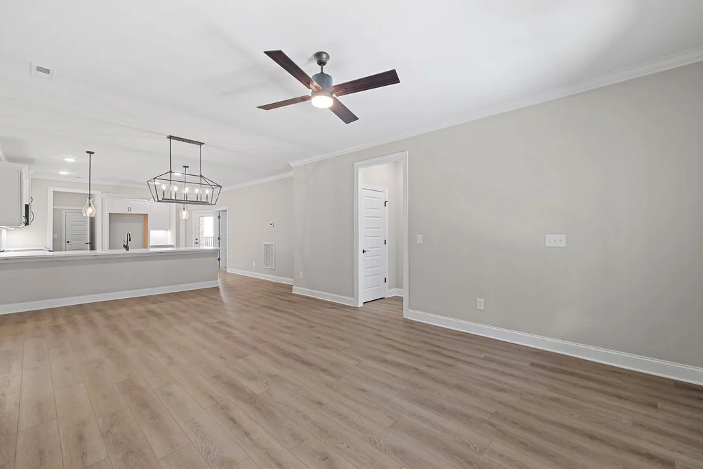New Home Chattanooga TN. Spacious open-concept living area with hardwood floors, ceiling fan, and modern kitchen lighting by Pratt Home Builders.