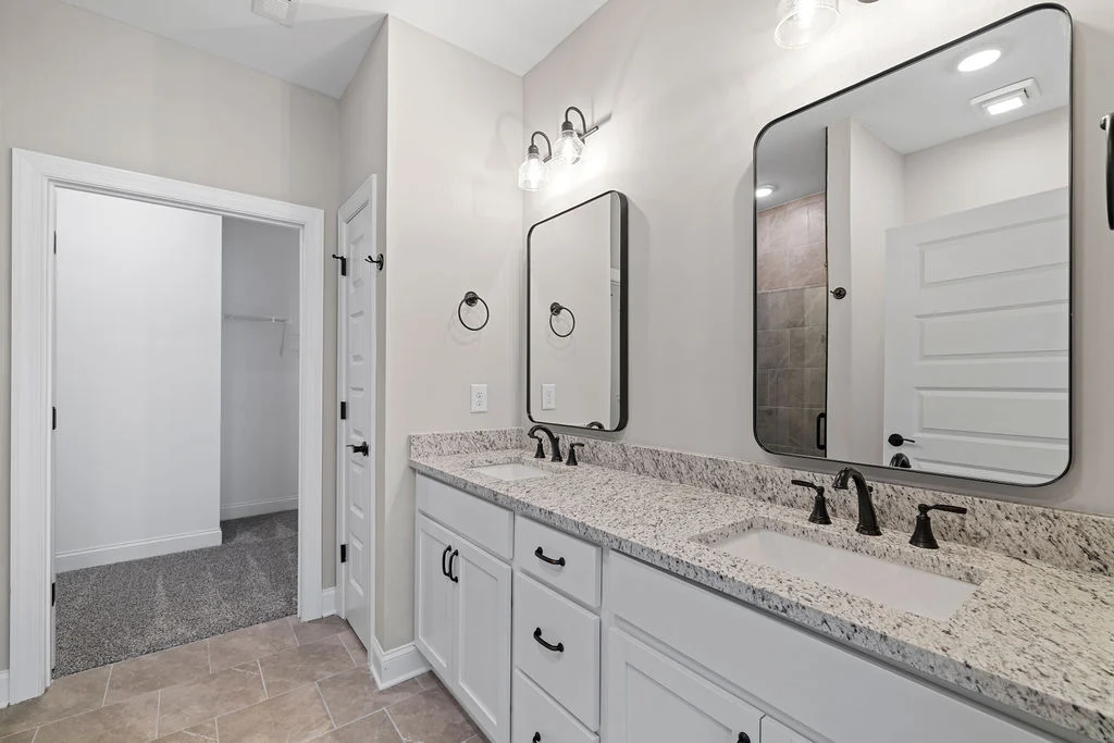 New Home Chattanooga TN. Modern bathroom with dual sinks, granite countertop, black fixtures, and large mirrors. Designed by Pratt Home Builders.