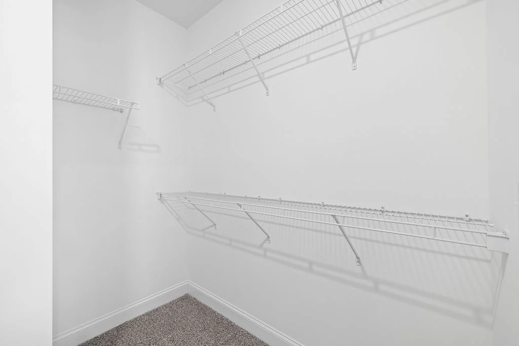 Spacious white closet with wire shelving by Pratt Home Builders in Chattanooga TN, carpeted floor, and simple design.