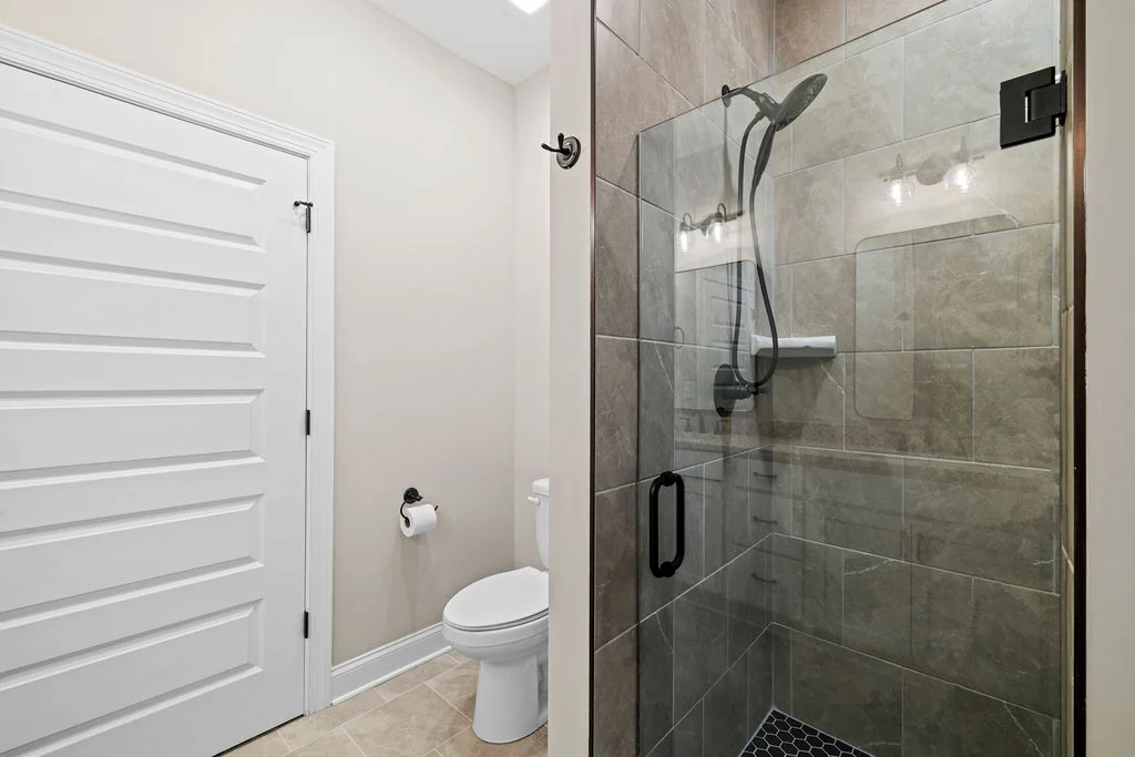 Modern bathroom with tiled shower, glass door, and toilet. Designed by Pratt Home Builders in Chattanooga TN.